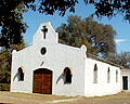Frente y lateral de la Iglesia de Luyaba sobre parque arbolado